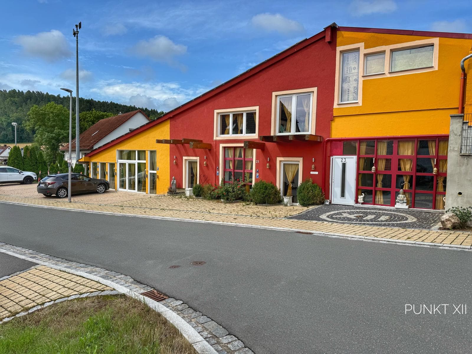 Die rot-gelben Häuser von Punkt XII mit Parkplatz an der Dorfstraße in Oberrimbach