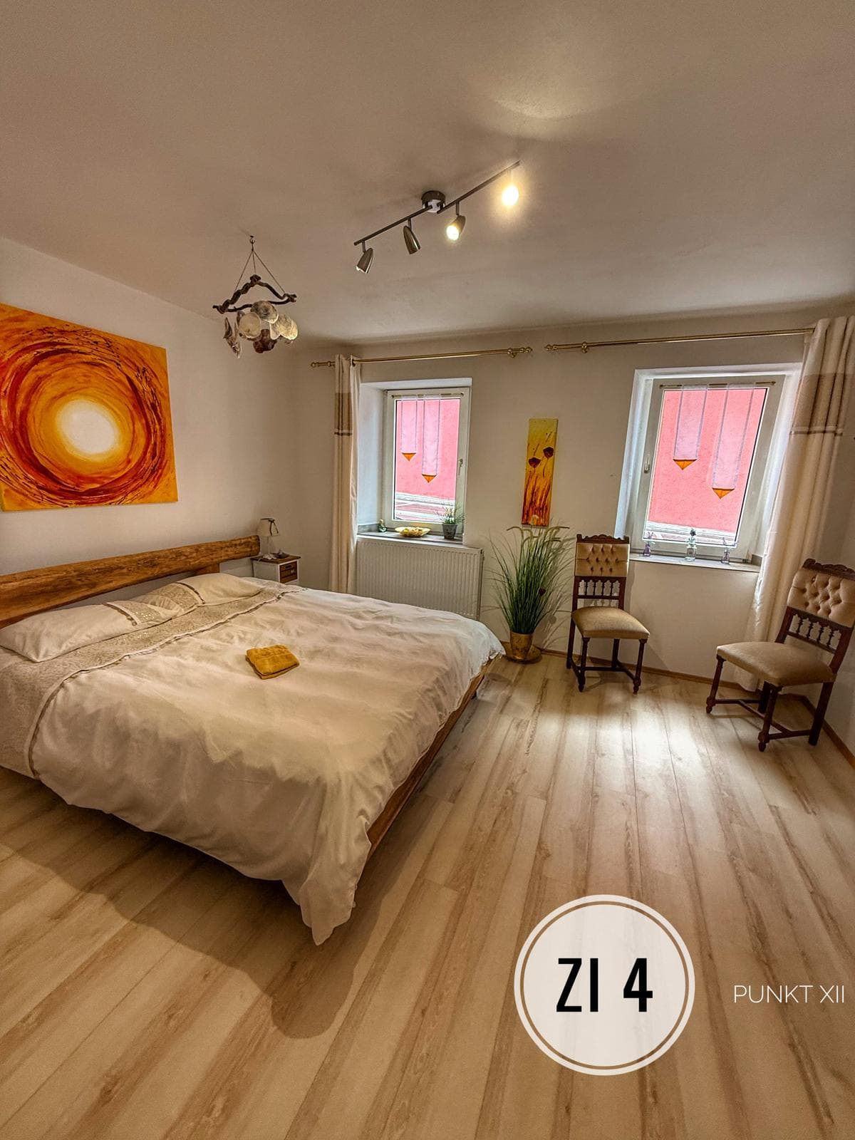 Zimmer 4 mit Doppelbett, Sonnenbild und zwei Fenstern