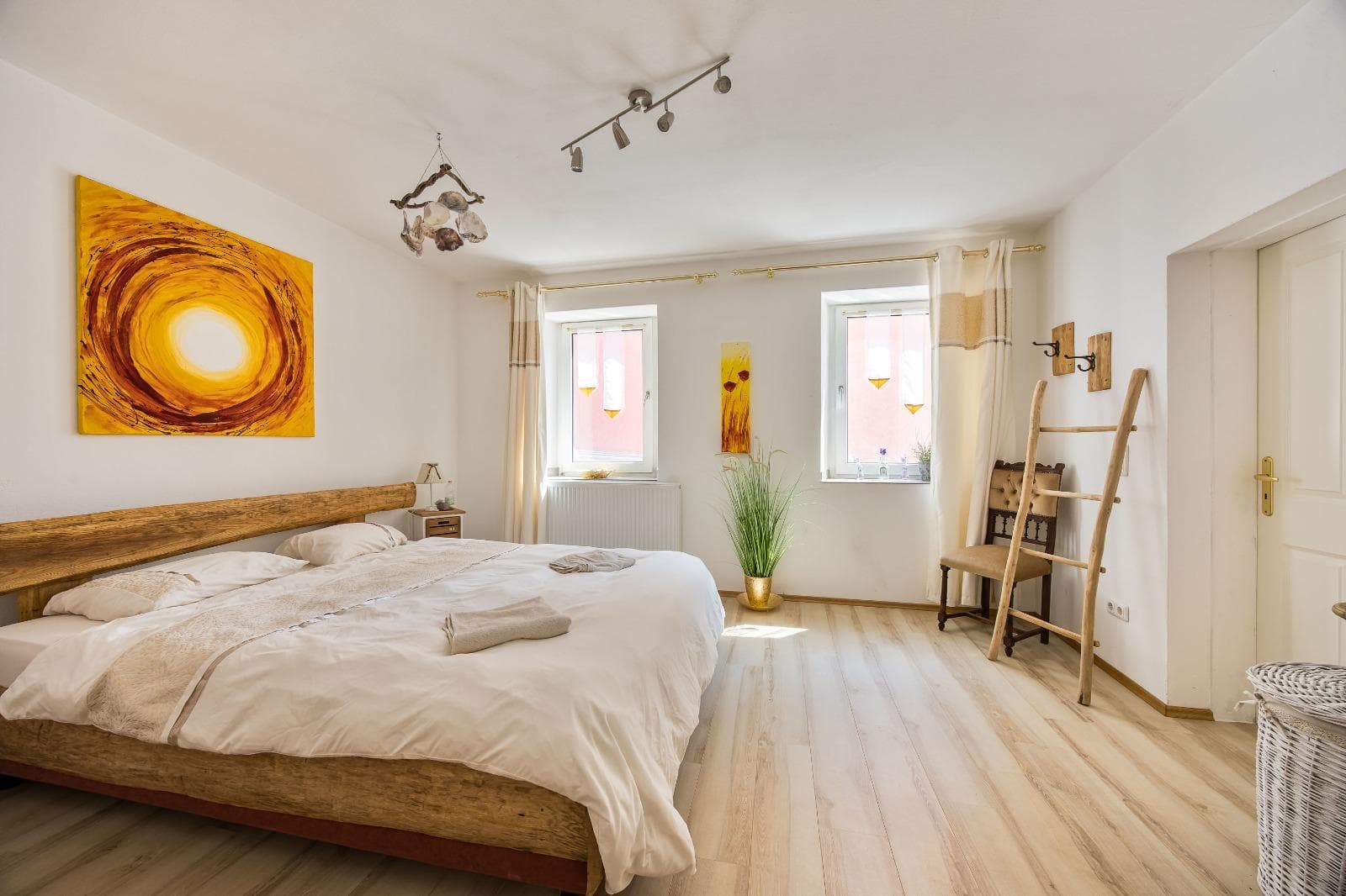 Helles Doppelzimmer mit Sonnenbild und Holzbett