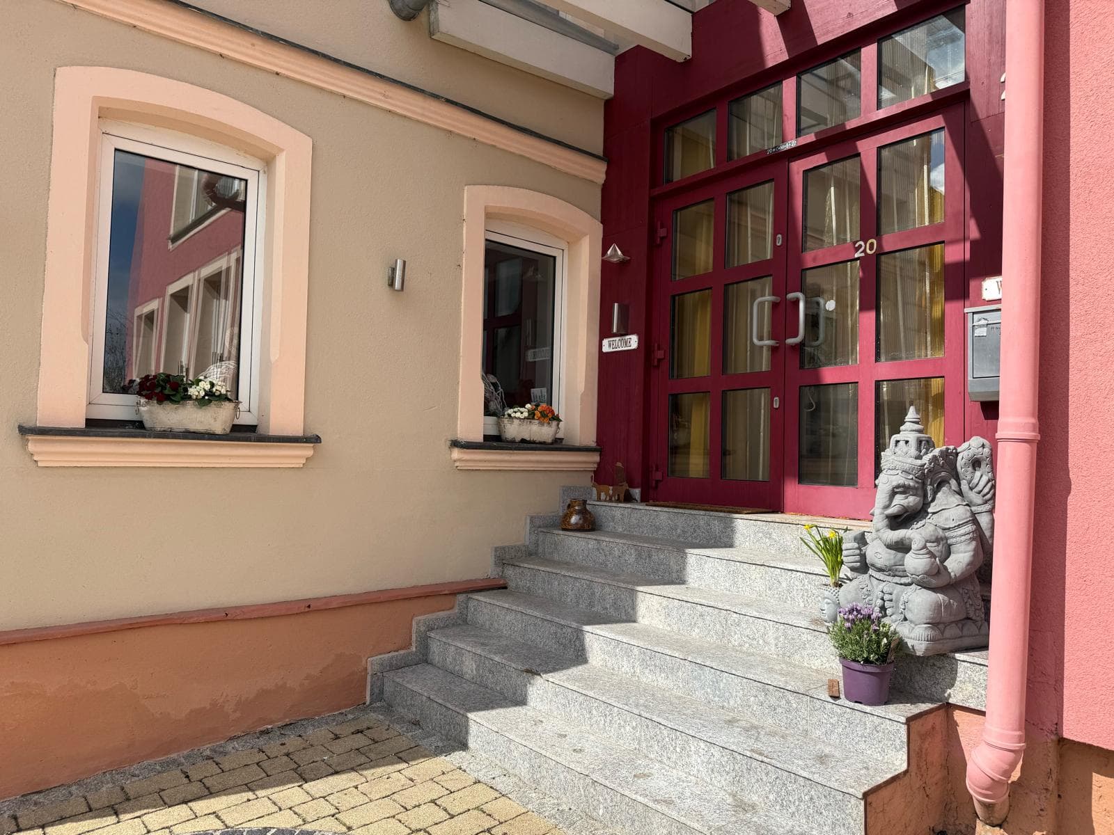 Einladender Eingang von Haus 20 mit Blumen, Willkommensgruß und Ganesha